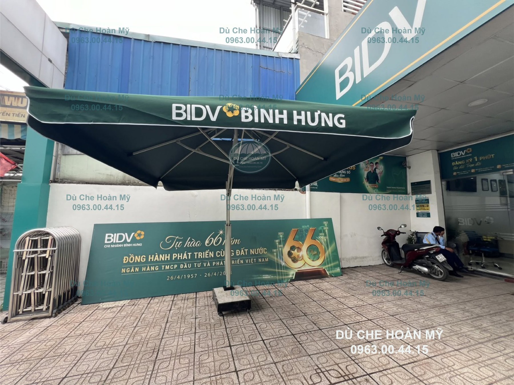 Dù lệch tâm vuông màu xanh in chữ BIDV Bình Hưng và logo trên diềm tán.