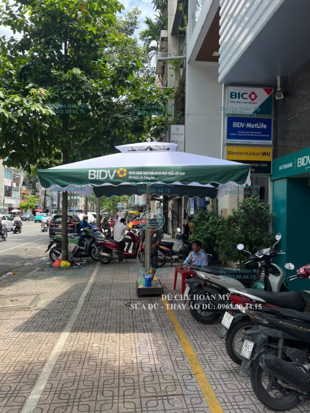 Dù in logo BIDV che vị trí gần nhân viên và xe máy trên mặt tiền điểm giao dịch.