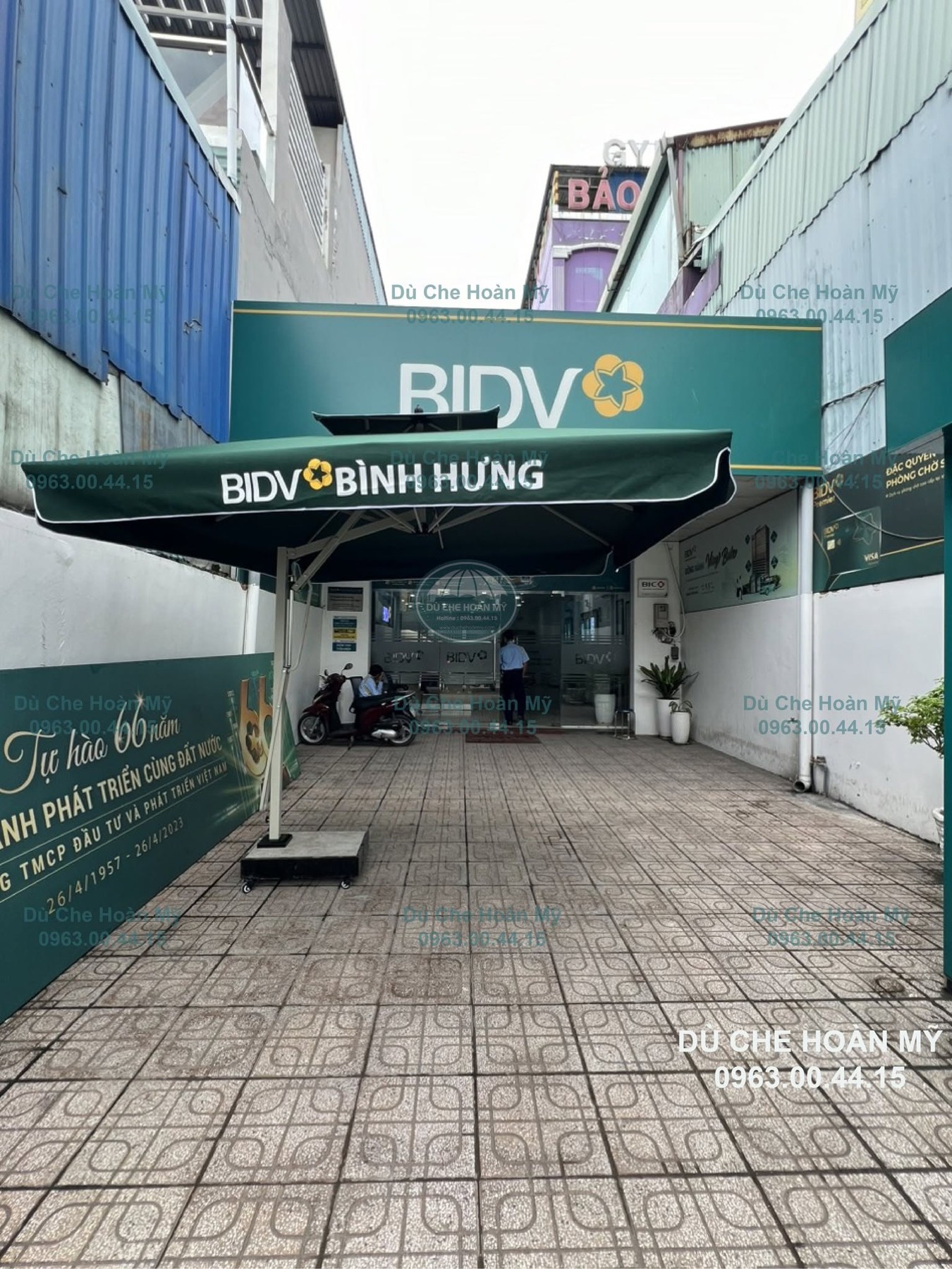 Dù BIDV Bình Hưng đặt trên khoảng sân lát gạch trước lối vào điểm giao dịch.